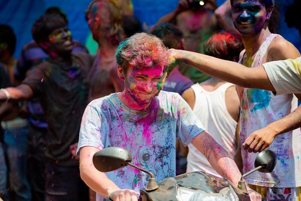 Viajante a passar de moto durante o Festival Holi na India | Happymind Travels